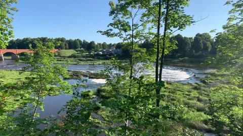 View of the river, waterfall, and arched bridge from the high bank Stock Footage 341404892