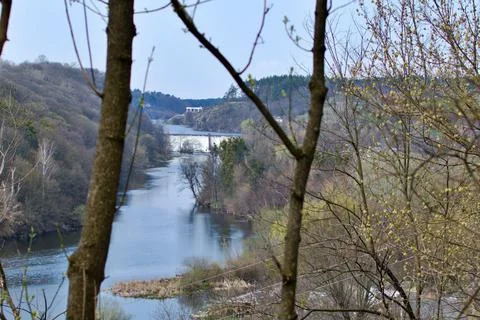 View of the river with waterfall through the trees of park Stock Photos