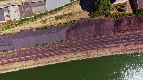 View of a riverbank with piles of material along the railway tracks during Stock Footage 344232547