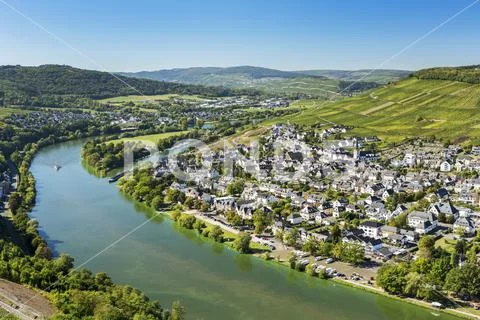 View of riverside village with bend in the river and steep vineyard slopes in th Stock Photos