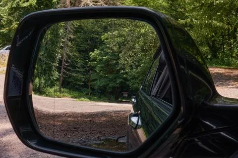 View of the road to the forest through the rearview mirror of the car. Stock Photos