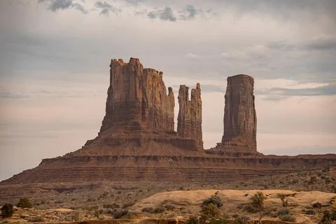 View of rock formations at Monument Valley with cloudy sky in background Stock Photos