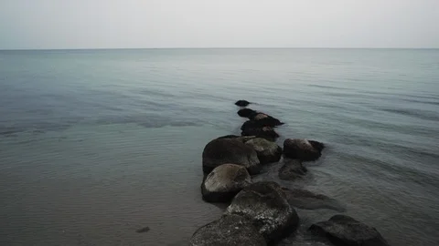 A view on a rock path into a calm sea in winter. Stockbeeldmateriaal 86563194