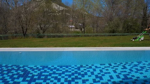 View of the rock. By the pool. Grass cutter. Man mows grass with a lawn mower Stock Footage 129503660