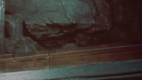 View of a rock wall with a ledge in a cave in a dark setting Stock Footage 345061236