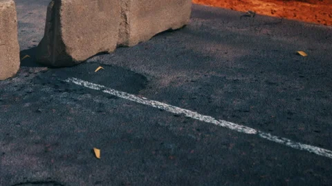 View of rocks on a black asphalt road with white road marking and leaves Stock Footage 344956542