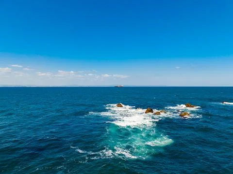 View of rocky ocean waves under a clear sky during daytime Stockfoto's