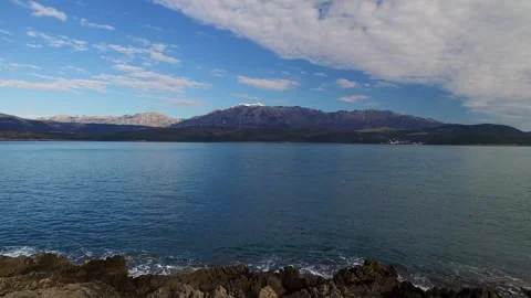 View from the rocky shore to the mountain range surrounding the bay. Aerial view Stock Footage 266808289