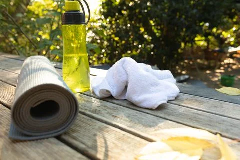 View of rolled yoga mat, white towel and yellow water bottle on terrace Stockfoto's