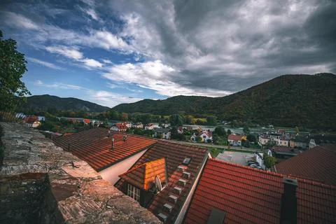 A view from a rooftop looking over a river, town, and mountains with a partially Stock Photos