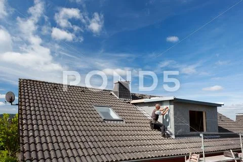View of a rooftop with a working roofer Stock Photos