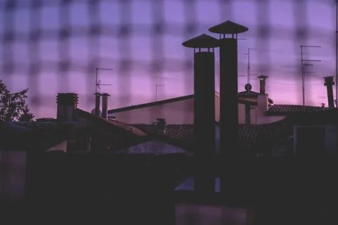 View of the rooftops of the city over the net illuminated by the sunset Stock Photos