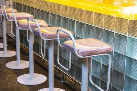 View of a row of bar stools that stand near a bar counter made of glass block Stock Photos