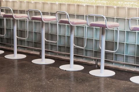 View of a row of bar stools that stand near a bar counter made of glass block Stock Photos