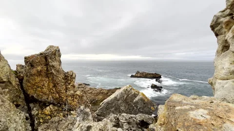 View from rugged coastal rocks of dolphin pod feeding on ocean surface Stock Footage 332586888