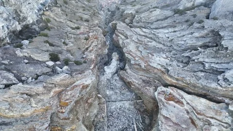 View into the rugged outflow canyon below Kawah Ijen dam, where gray rock plates Stock Footage 329430546
