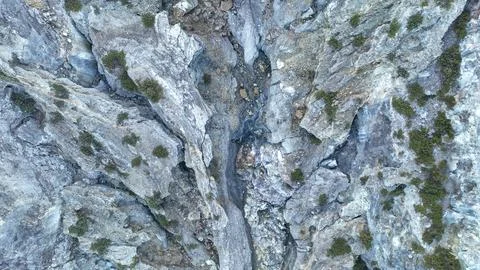 View into the rugged outflow canyon below Kawah Ijen dam, where gray rock plates Foto stock