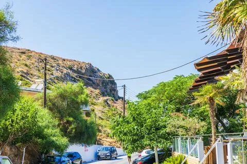 View of runner on residential street beside rocky mountain in sunny village. Stock Photos