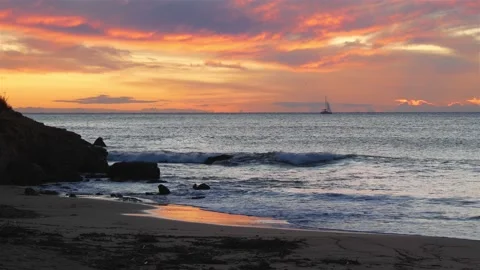 View From The Sandy Beach Of A Beautiful Sunset Over The Sea With A Sailing Boat Stock Footage 230095795
