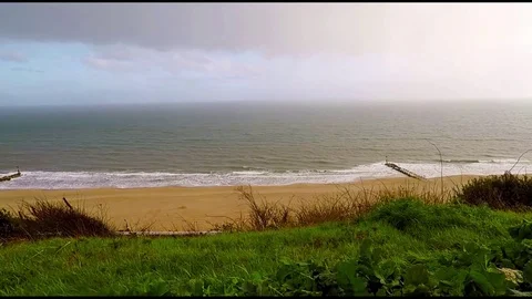 View of the sandy beach with hills on a rainy day, green vegetation, rain Stock Footage 78158731
