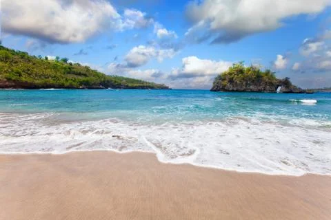 View from a sandy beach on rocks at ocean. Indonesia, Bali Stock Photos