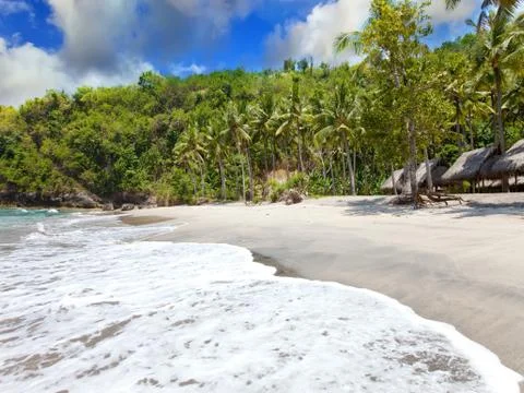 View from a sandy beach on rocks at ocean. Indonesia, Bali Stock Photos