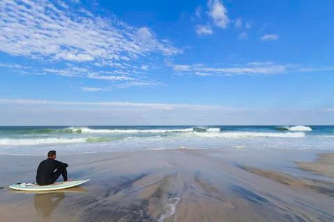 View of a sandy beach with a surfer. Stock Photos