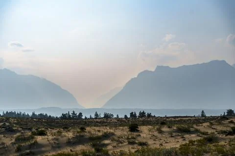 View of a sandy plateau surrounded by forest and mountains Stock Photos