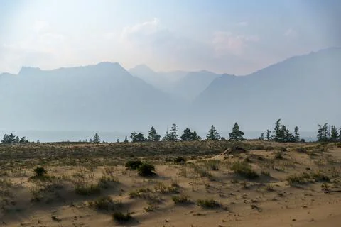 View of a sandy plateau surrounded by forest and mountains Stock Photos