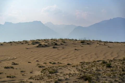 View of a sandy plateau surrounded by forest and mountains Stock Photos