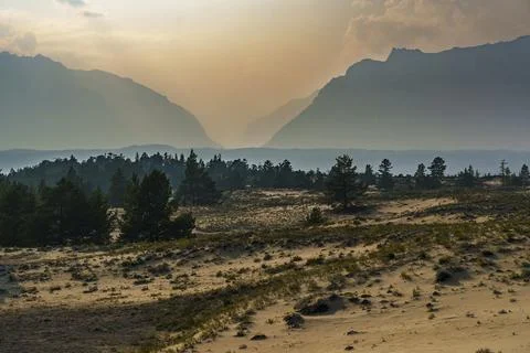 View of a sandy plateau surrounded by forest and mountains Stock Photos