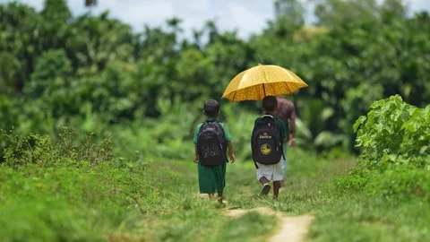 View of school children walking with a yellow umbrella, Bangladesh. Video stock 335584964