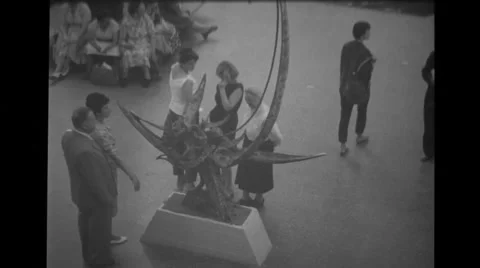 View of sculpture and visitors sitting around tree at Brussels World's Fair Stock Footage 37595075