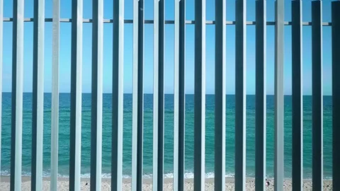 View of sea and beach from window of moving train. Beach is visible trough fence Stock Footage 118433902