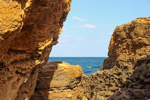 View of the sea from between two rock formations on a sunny day Stock Photos