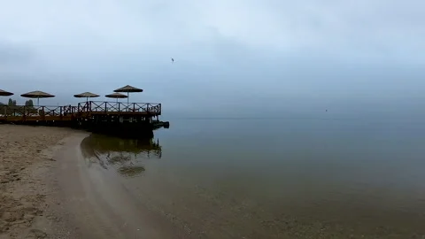 A view of the sea in calm, windless, overcast weather with grey rainy clouds Video stock 330856436