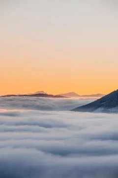 View of sea of clouds colored in the soft orange-pink hue of the morning sun. Stock Photos