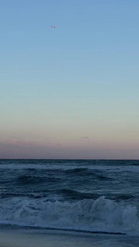 View of sea during storm with airplane flying over horizon at sunset. Vertical Stock Footage 240921445