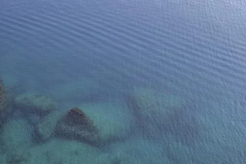 View of the sea surface from above. Stone blocks are visible under water. Stock Photos