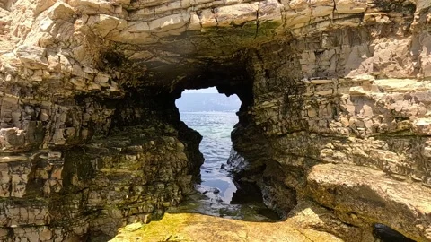 View of the Sea Through an Opening in a Rock Stock Footage 265602841