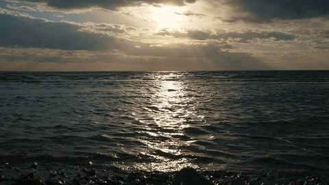 A view of the sea with waves, the rays of the sun through dark clouds. Dramatic Stock Footage 91560951