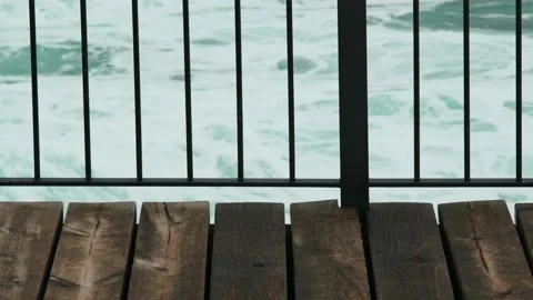 View of the sea waves through the lattice of the balcony. White sea foam bubbles Stock Footage 178955233