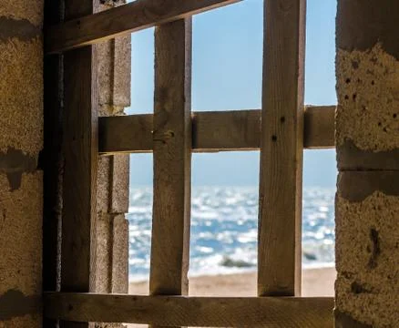 View of the seashore through the boarded up window Stock-Fotos
