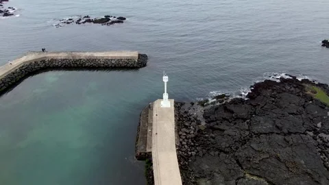 The view of the seawall and lighthouse guarding the sea on the emerald beach of Stock Footage 279566632