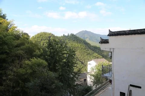 The view from the second floor of an old white-walled house shows green mou.. Stock Photos