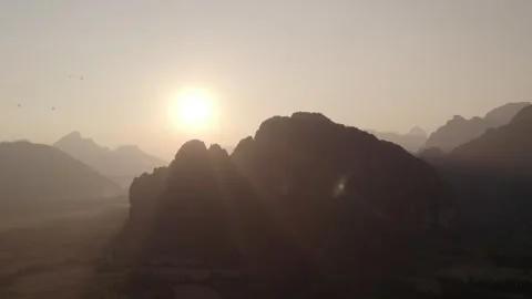 View of the setting Sun behind large mountains Stockbeeldmateriaal 330065162