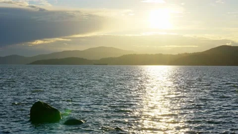 View of the setting sun over the sea horizon from the top a hill Stock Footage 157249744