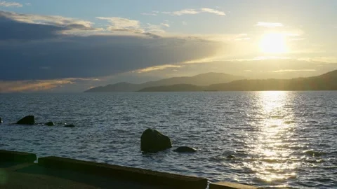 View of the setting sun over the sea horizon from the top a hill Stock Footage 157249846