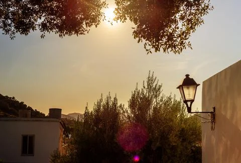 View of the setting sun from the side of the house with a lantern surrounded Stock Photos