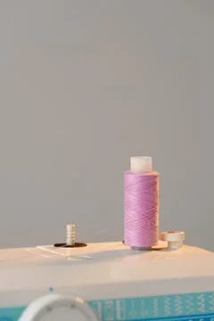 View of a sewing machine with a spool of pink thread placed on top Stock Photos